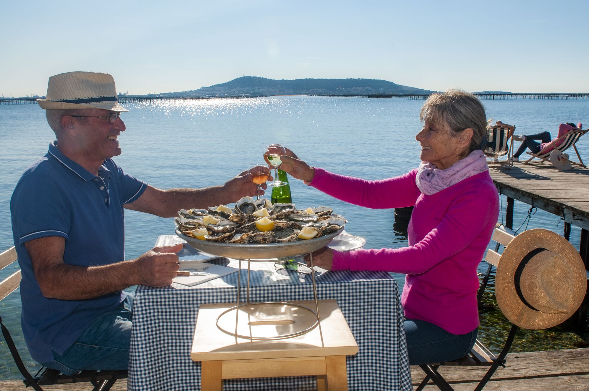 Couple de jeuniors en train de boire un verre de vin et manger des huîtres au Petit Mas Loupian, au bord de l'Etang de Thau ©D.Cavailhes
