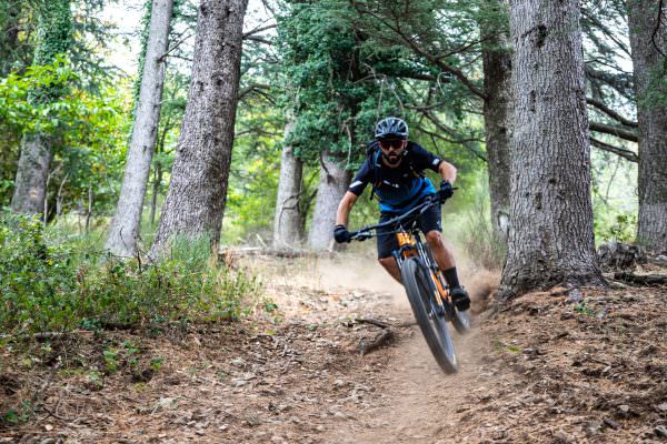 un vététiste en descente dans la forêt