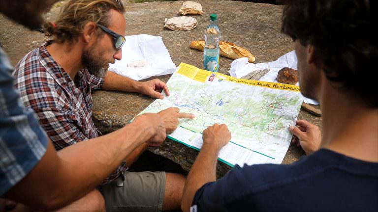 des vététistes regardent une carte de parcours pendant leur pique-nique