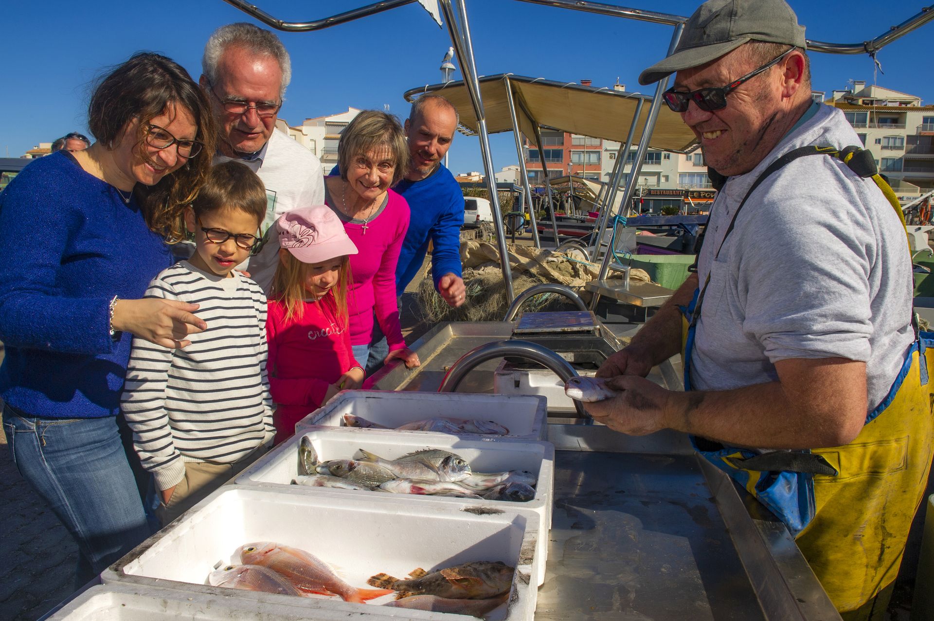 Famille qui achète du poisson à un pêcheur sur le port du Cap d'Agde