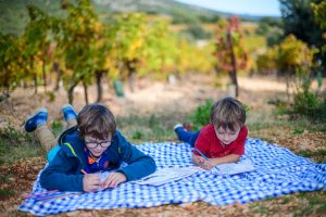 Deux enfants, un moment de détente au pied des vignes. Coloriage sur la nappe de pique-nique