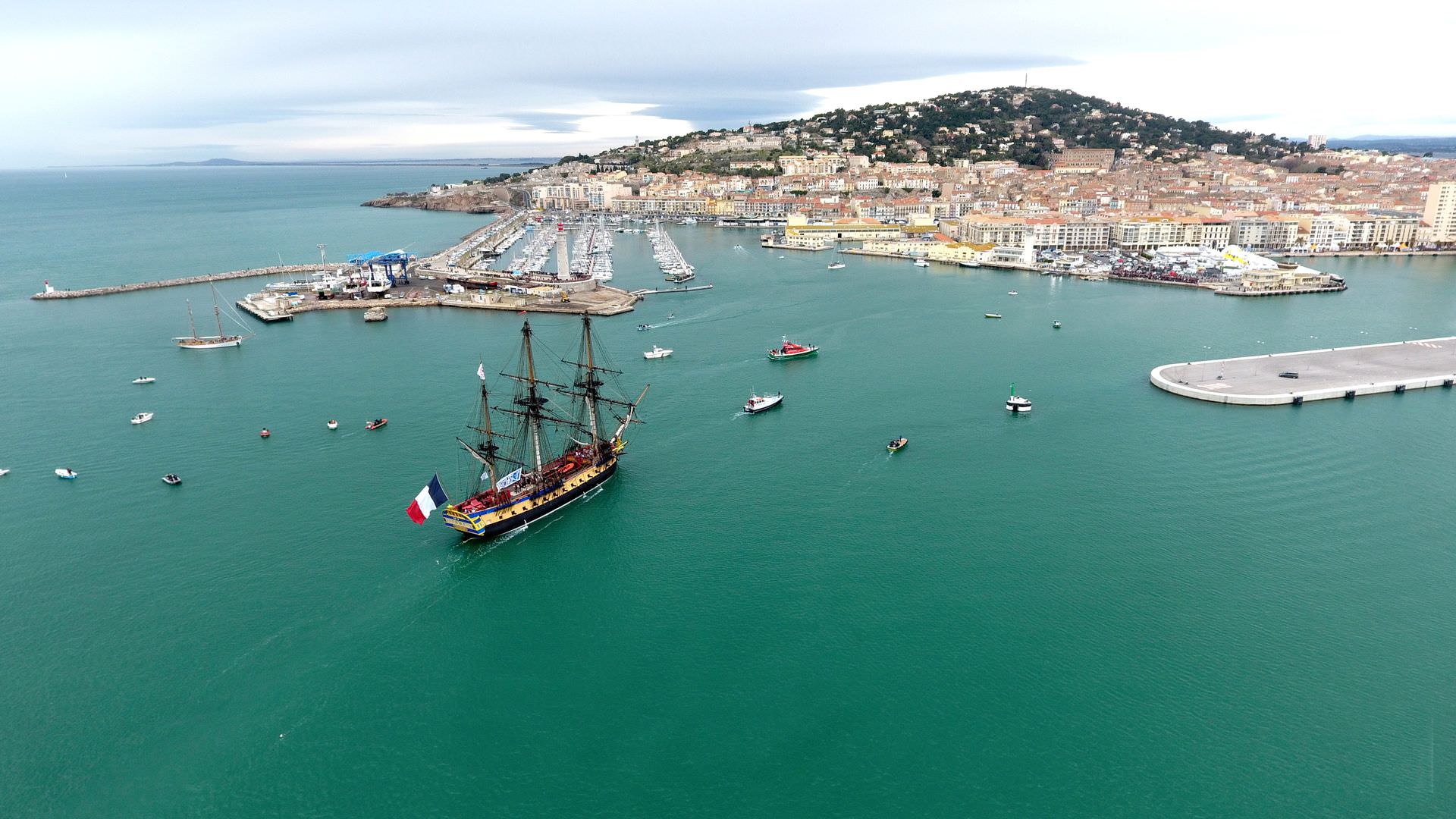 Grand voilier ancien et autres bateaux avec la ville de Sète en arrière plan dans le cadre du festival Escale à Sète