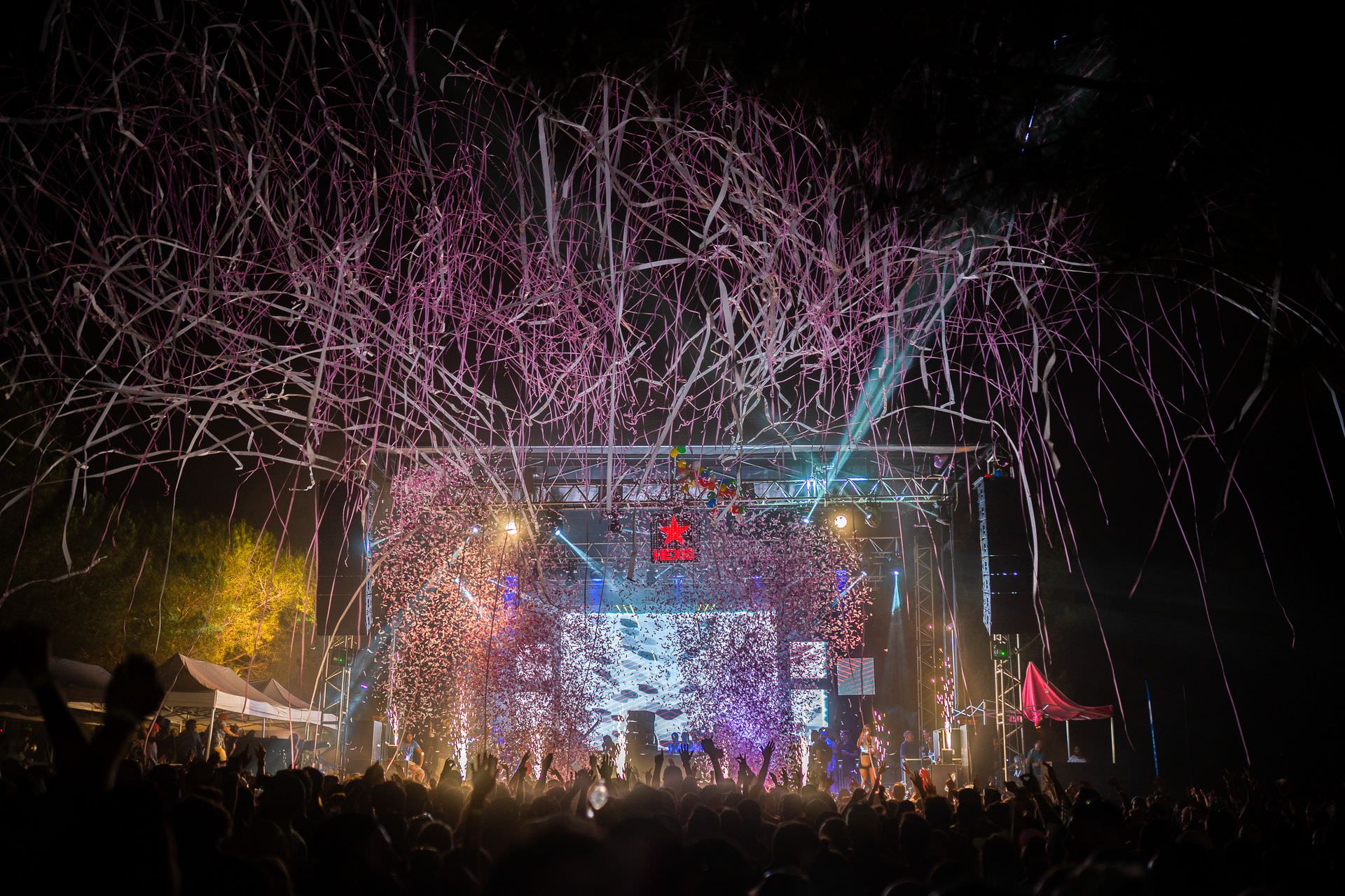 Pluie de cotillons et confettis roses au-dessus de festivaliers qui dansent devant la scène de la Family Piknik à la nuit tombée