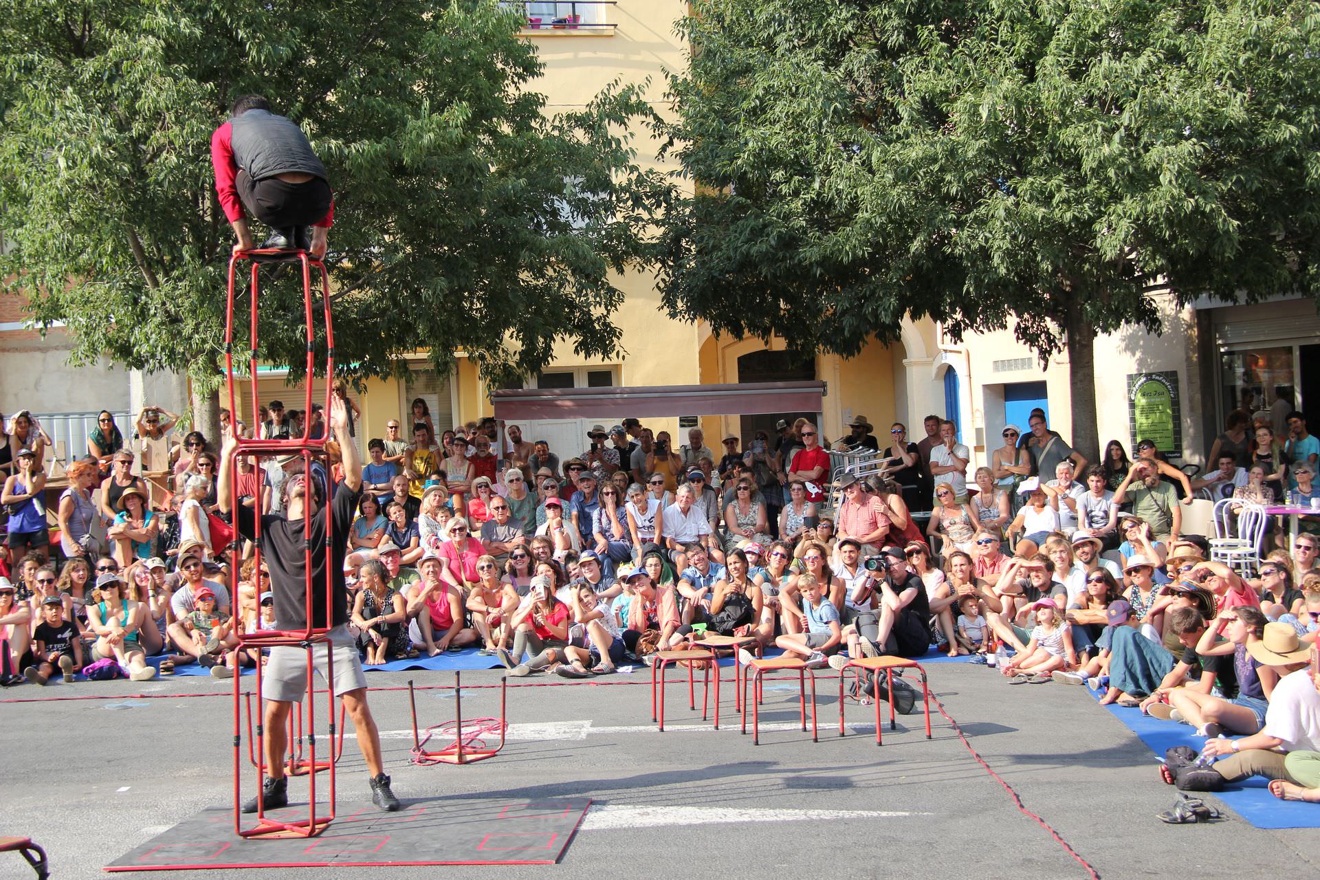 Duo d'acrobates du cirque Bankal faisant un spectacle de rue à Lodève devant une foule de visiteurs en famille dans le cadre du Festival Résurgence en été