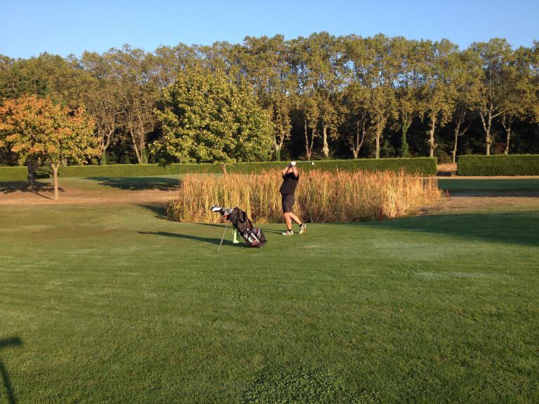 Joueur de golf qui lève son club en l'air prêt à taper dans la balle sur le terrain de golf de Lamalou les Bains