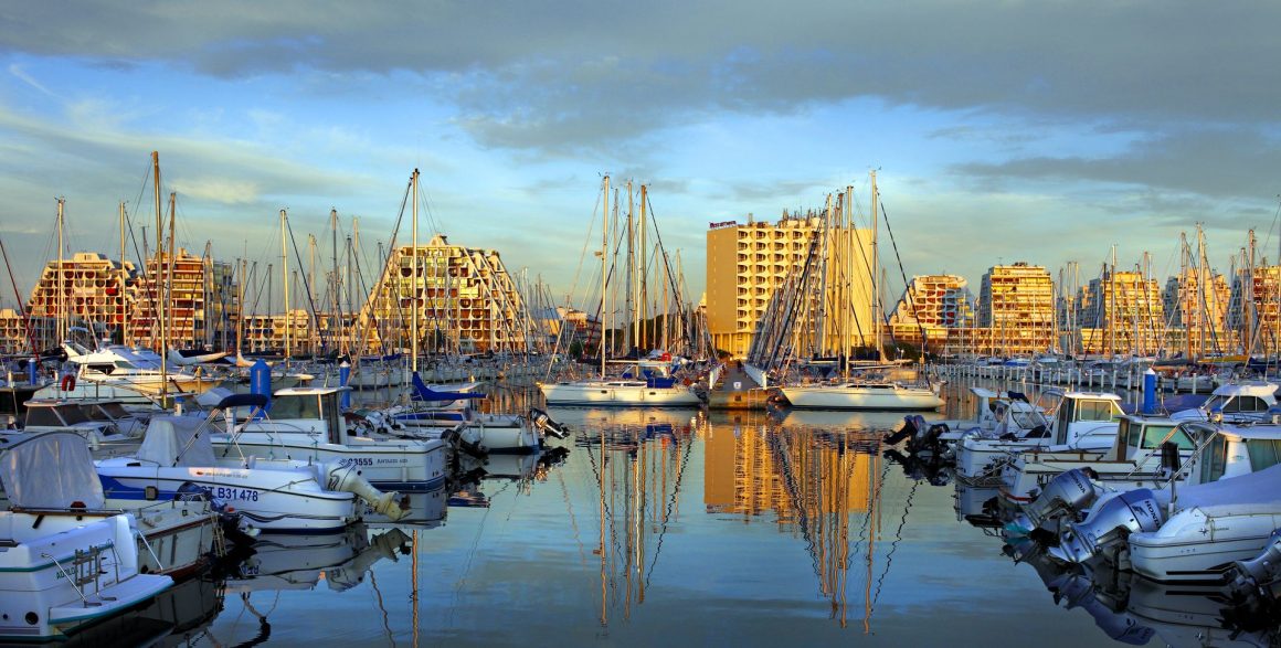 Vue sur le port et les bateaux de La Grande Motte avec le soleil couchant sur les bâtiments en arrière-plan