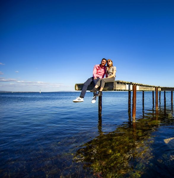 Couple de jeunes assis sur un ponton au dessus de l'étang de Thau
