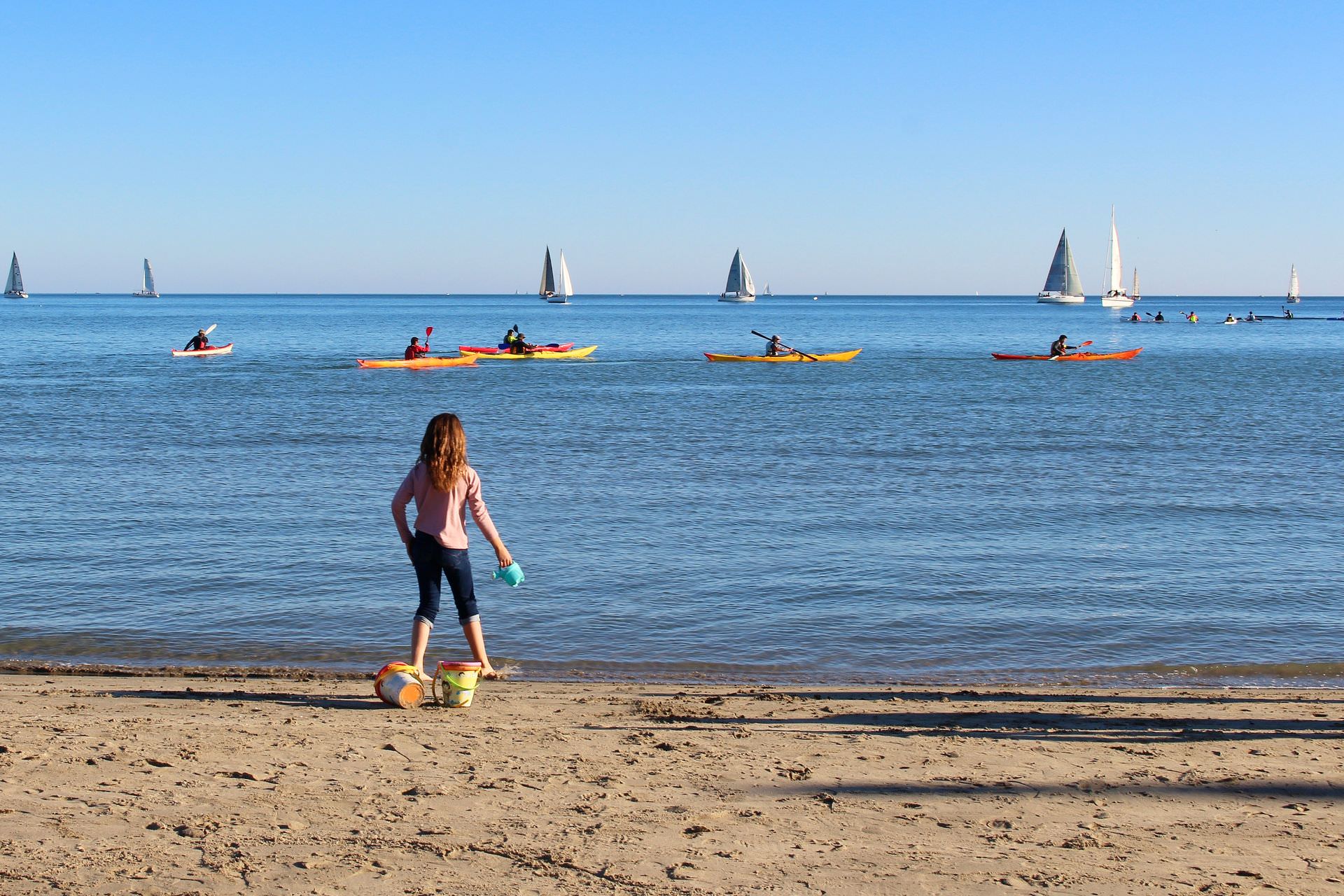 Enfant qui joue sur la plage à Palavas-les-Flots rive gauche avec des bateaux et canoës en fond