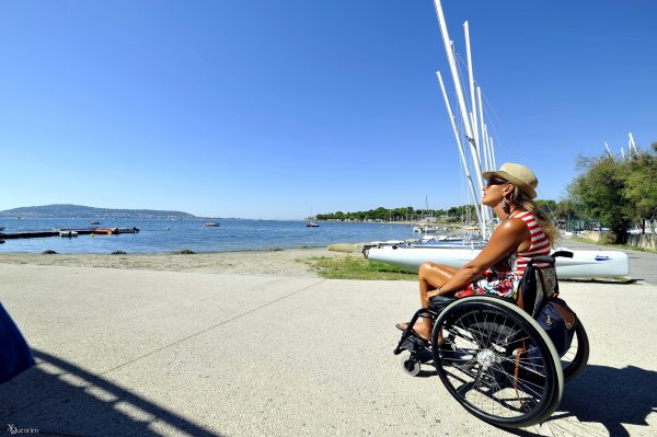 Une jeune femme en fauteuil chemine vers les bateaux de Manureva