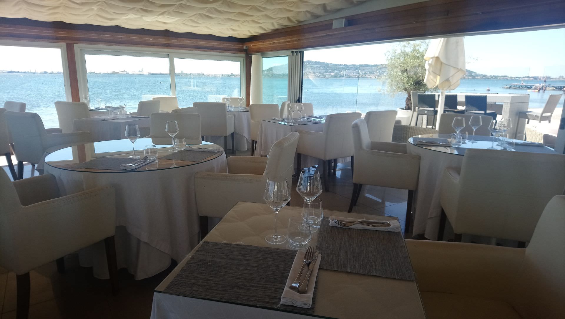 Tables dans un restaurant devant l'étang de Thau avec la colline de Sète en arrière-plan