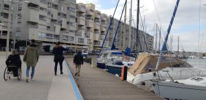 Personnes en situation de handicap moteur et visuel qui se déplacent au bord du port de Carnon