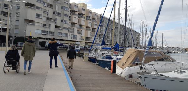 Personnes en situation de handicap moteur et visuel qui se déplacent au bord du port de Carnon