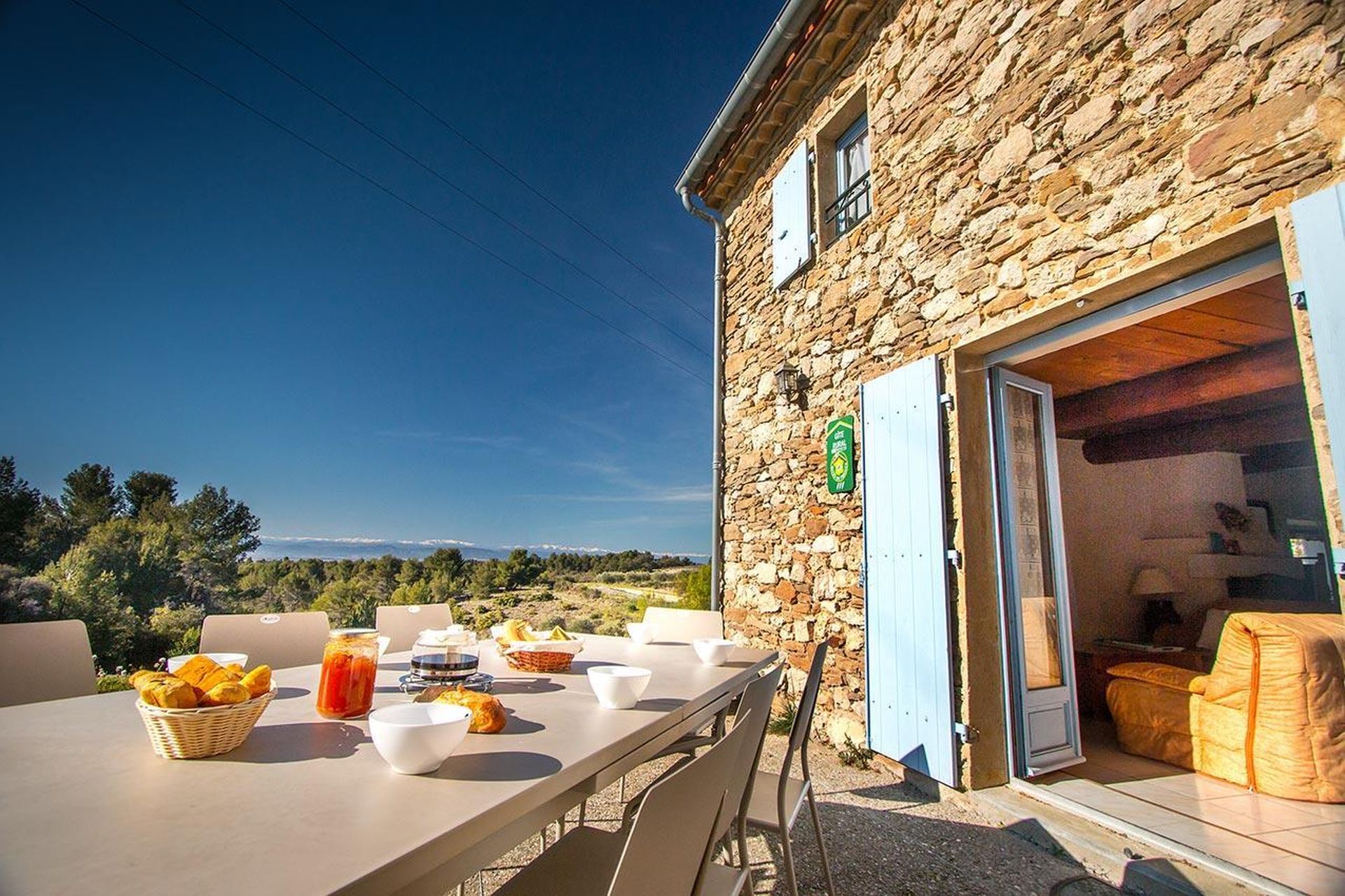 Petit déjeuner sur la terrasse d'un gîte avec cheminée dans le Minervois, avec vue sur les Pyrénées