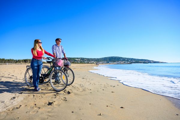 Couple qui se balade en vélo le long du lido entre Sète et Marseillan et qui observe la Méditerranée