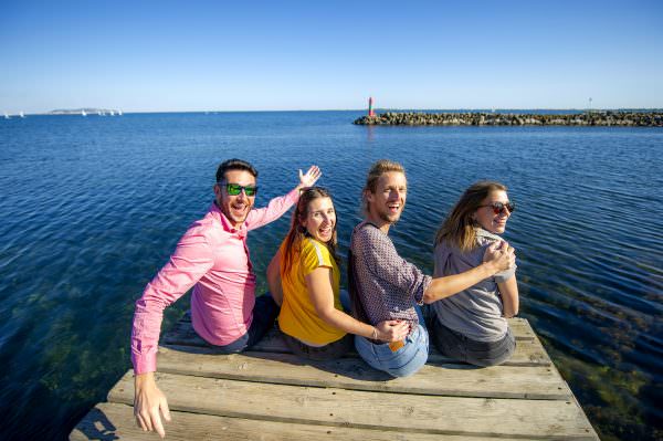 Jeunes assis sur le ponton de Marseillan et qui saluent le photographe © ADT 34 Didier Cavailhes