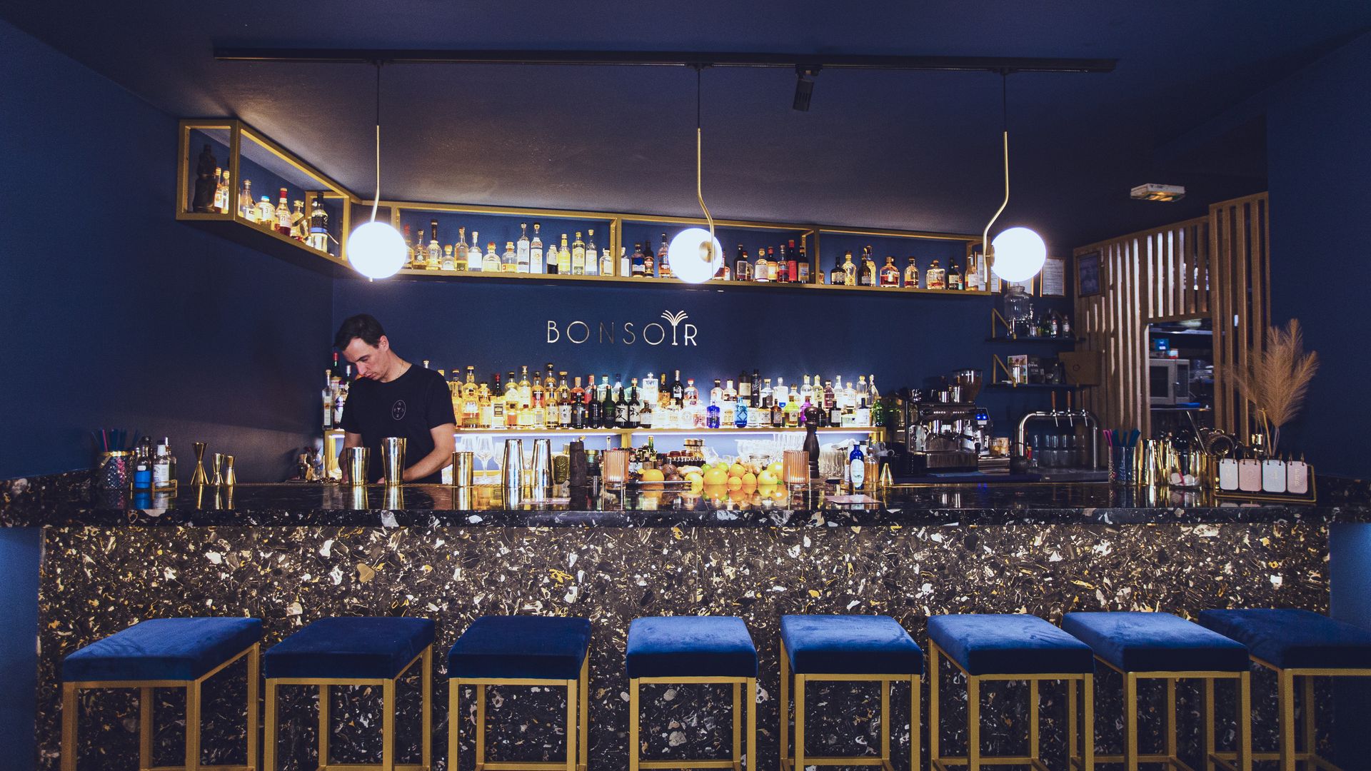 Serveur en train de faire un cocktail derrière le bar bleu et or du Bonsoir Cocktail