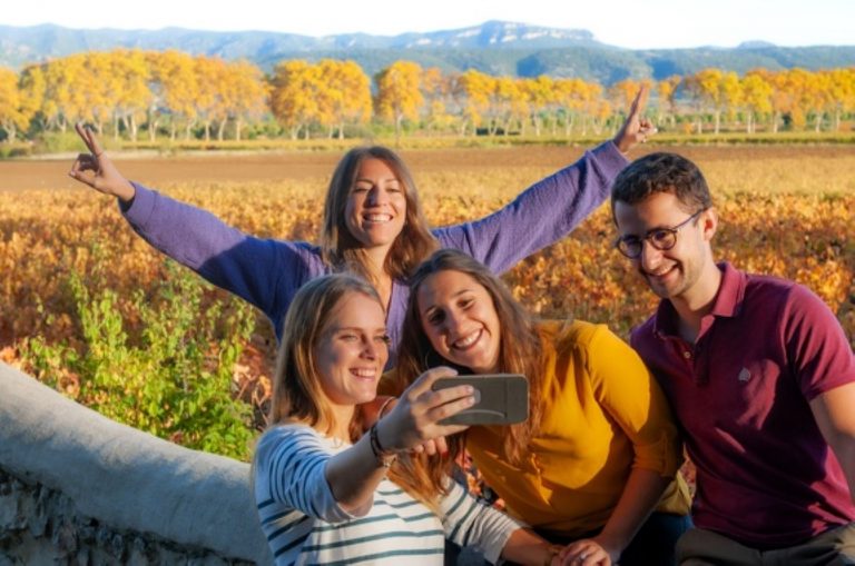 Un groupe de jeunes gens font un selfie au coucher de soleil dans les vignes
