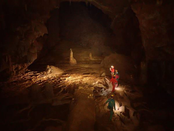 Des hommes explorent une cavité à la lampe frontale lors d'une séance de spéléologie dans l'Hérault