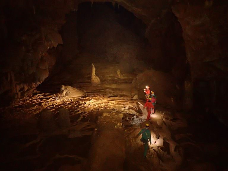 Des hommes explorent une cavité à la lampe frontale lors d'une séance de spéléologie dans l'Hérault