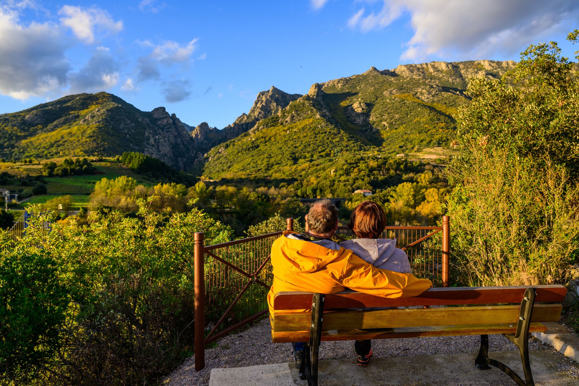 Couple assis sur un banc admirant les montagnes du Caroux depuis Tarassac