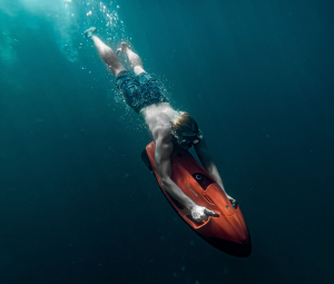 Un homme plonge dans la mer avec un scooter sous-marin