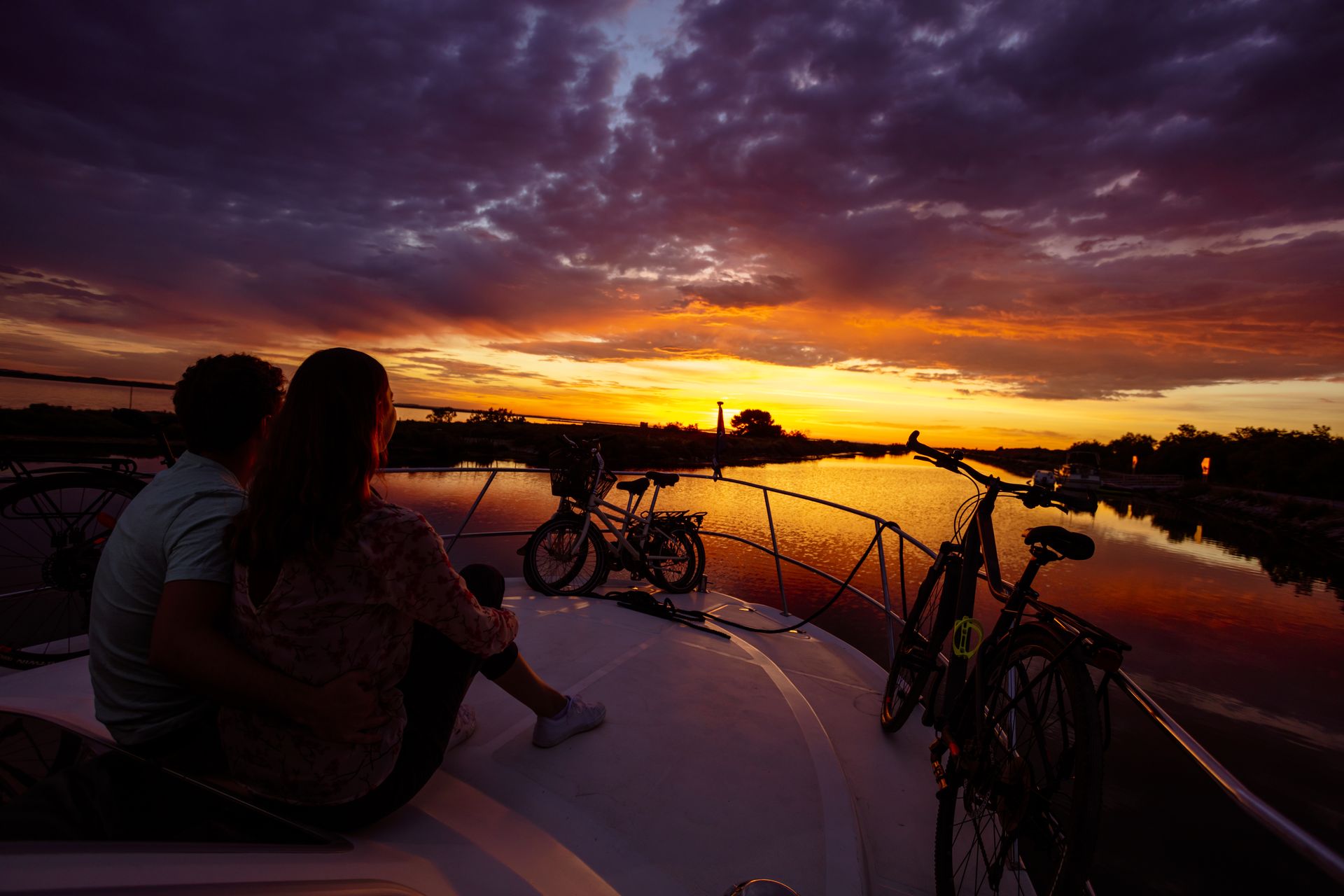 Couple sur une péniche sur le Canal du Rhône à Sète en admiration devant un beau coucher de soleil