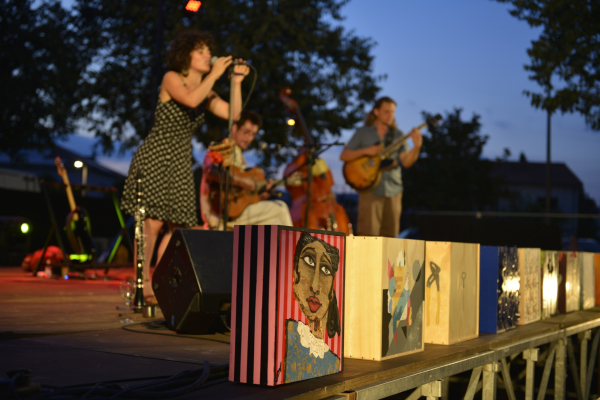 Dans une soirée, sous un arbre, un groupe se produit sur scène avec une chanteuse