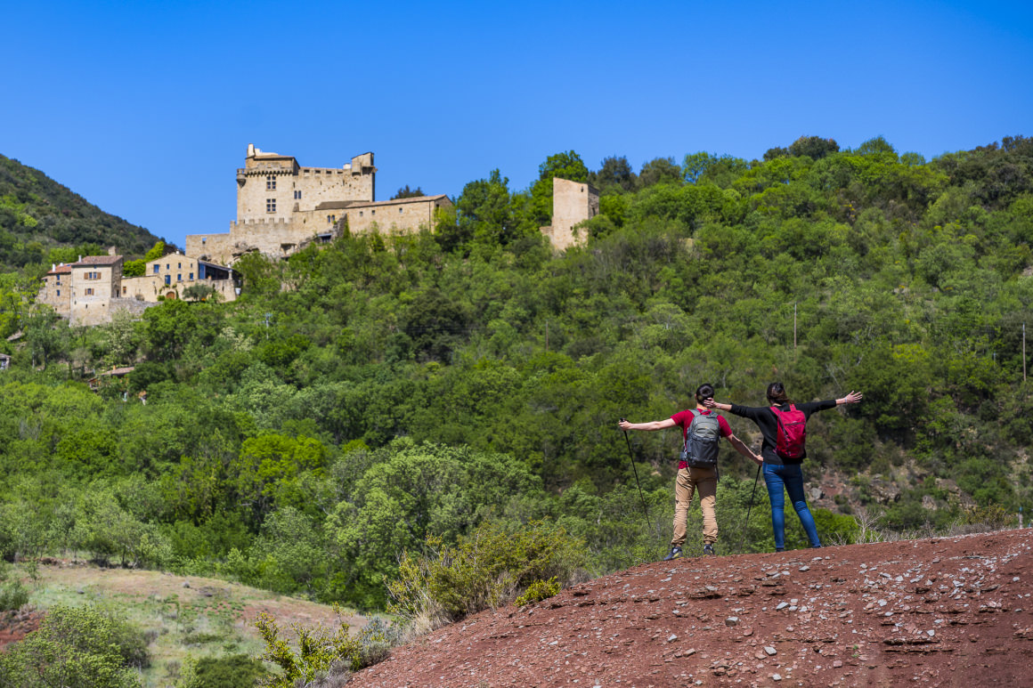 Randonneurs sur les terres rouges au pied du Château de Dio