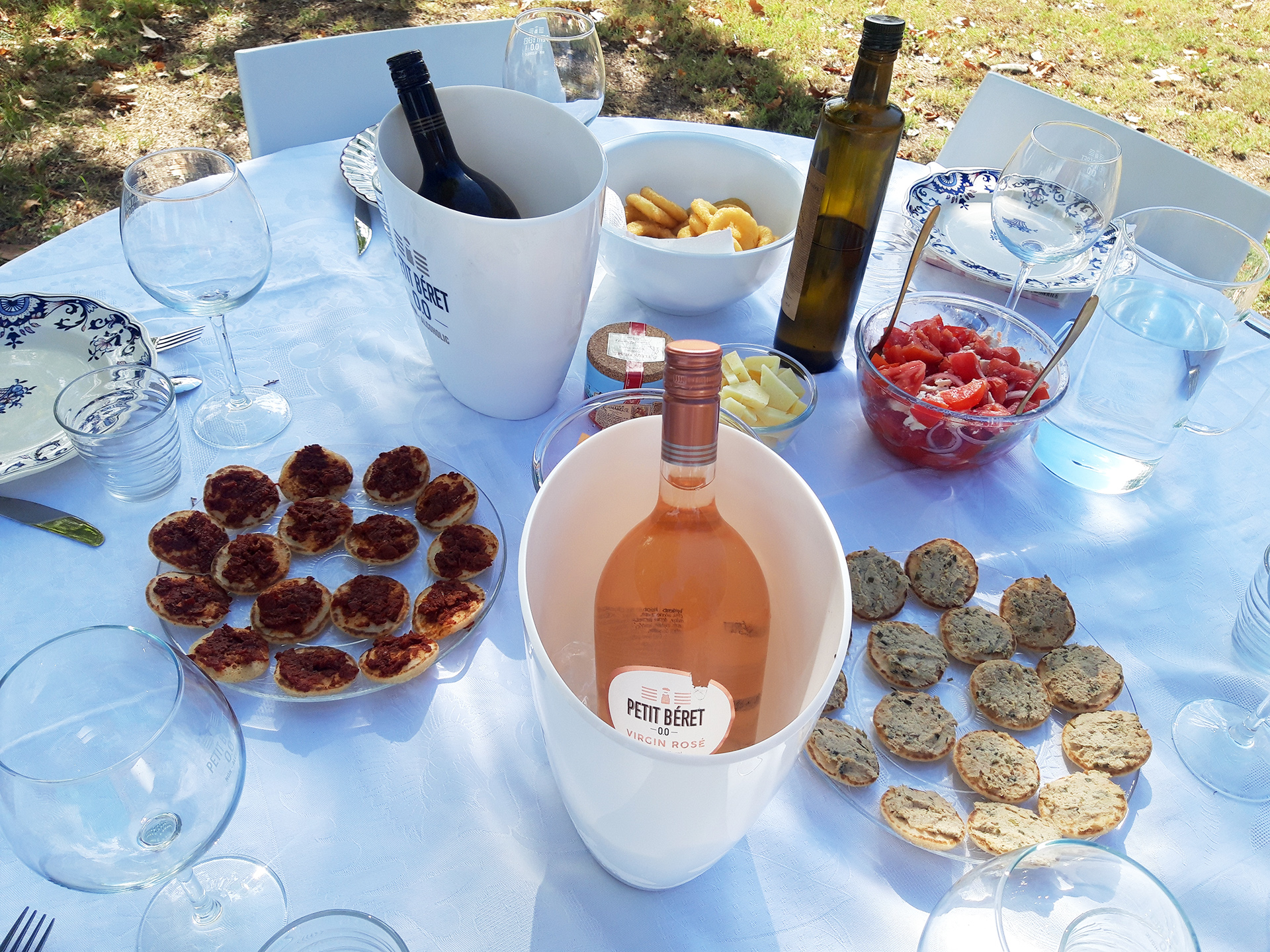 Petits toasts disposés sur une table en extérieur avec des bouteilles de rosé et rouge de Petit Béret