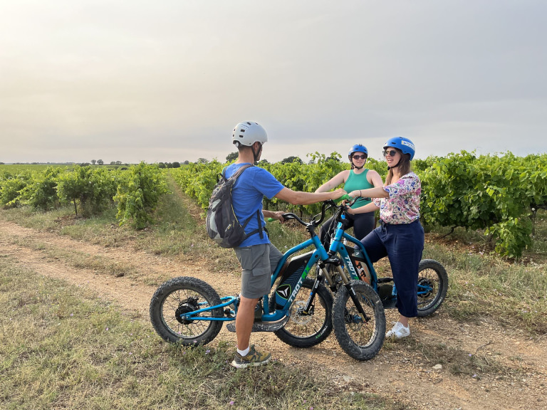 Trois jeunes font de la trottinette électrique dans les vignes