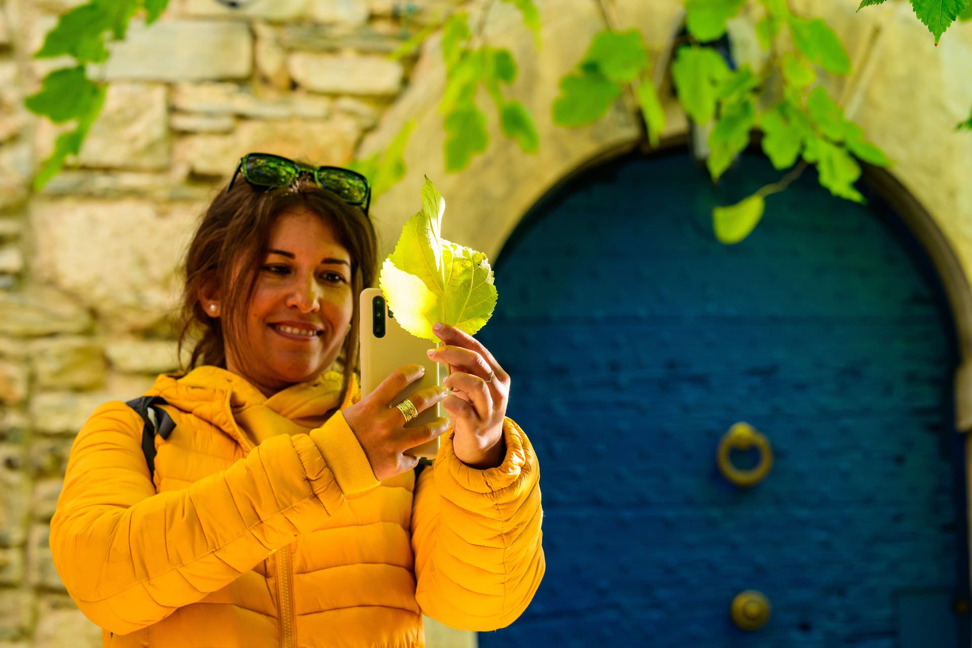 Mary Barral de l'Office de Tourisme du Minervois au Caroux en Haut-Languedoc prend une photo d'une feuille morte avec son portable dans le village de Vieussan