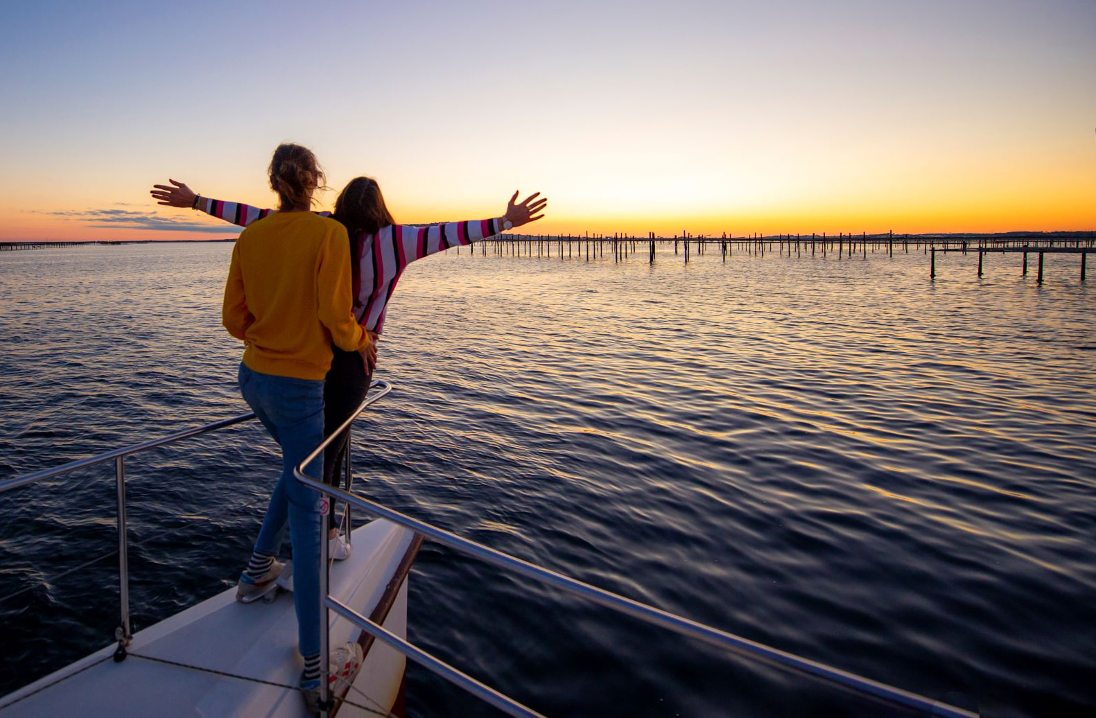 Couple qui regarde un lever de soleil sur un bateau sur l'étang de Thau