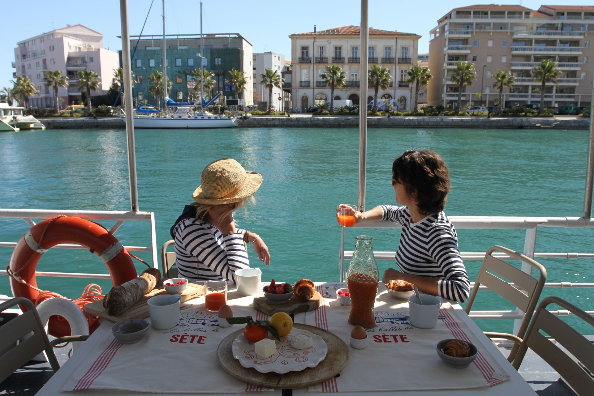 Deux amies petit-déjeunent sur la terrasse de la péniche Anna Maria 4 accostée au quai de la république à Sète