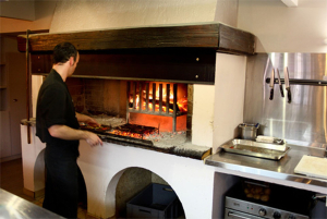 Chef cuisinier du restaurant Au feu de bois à Sète devant la cheminée du restaurant