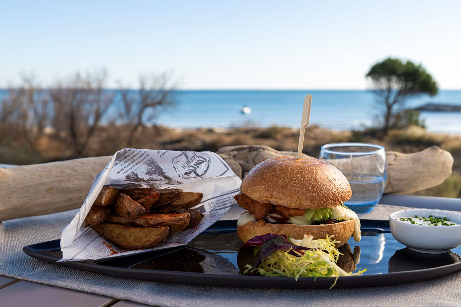 Hamburger avec frites dans un cornet sur la terrasse face à la mer