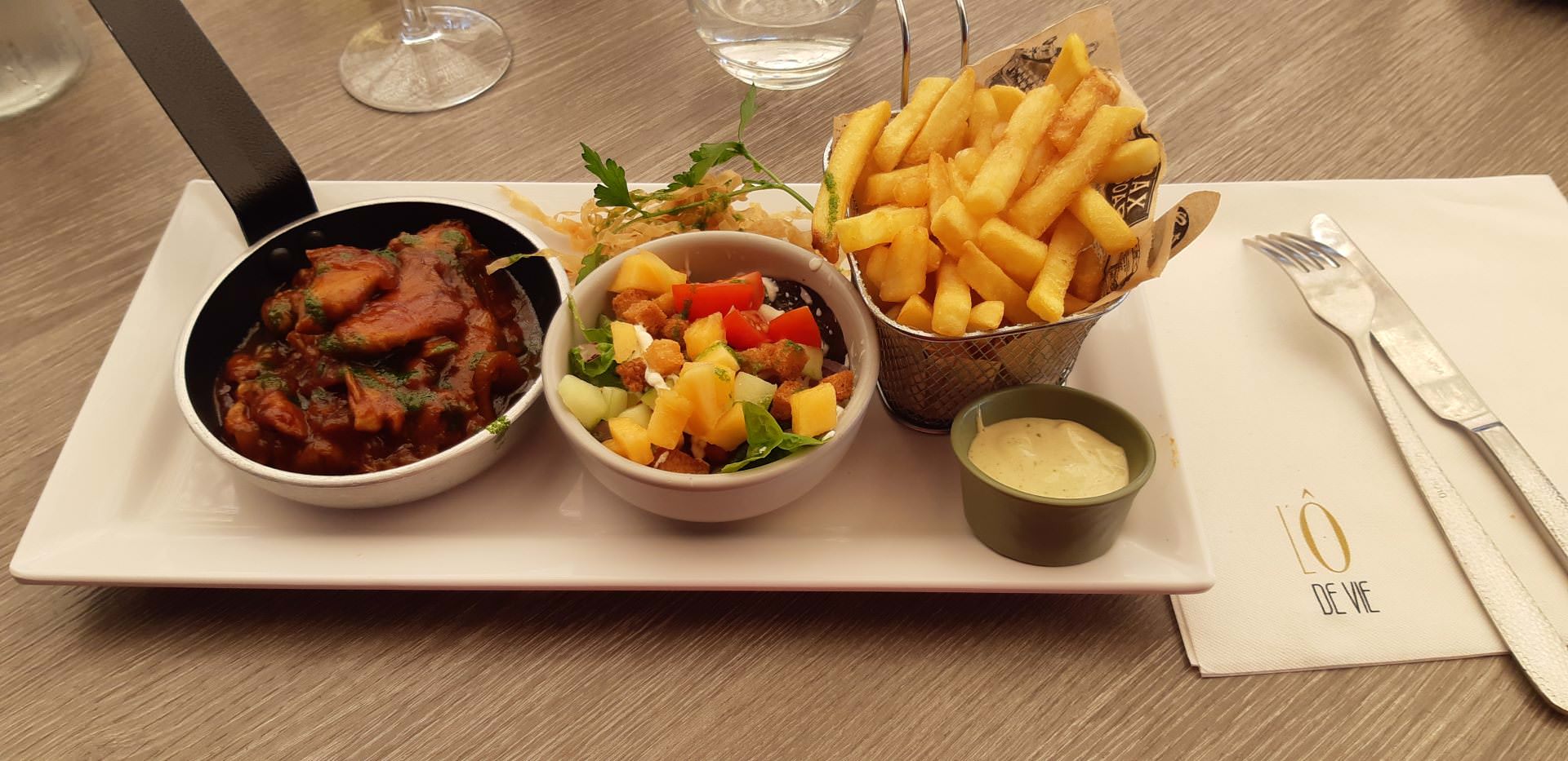 Plat servi au restaurant l'O de Vie. Un poêlon avec du poulet caramélisé, un ramequin avec des légumes et un autre ramequin avec des frites