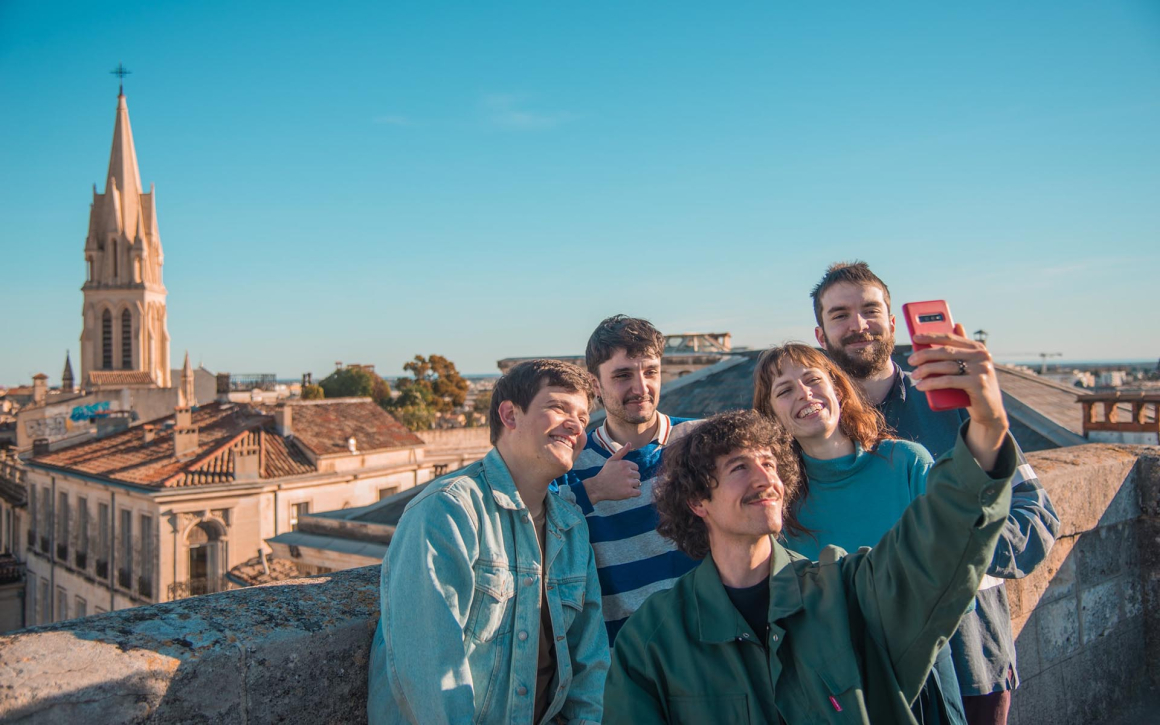 Groupe de jeunes se prenant en selfie sur l'arc de Triomphe à l'occasion d'une visite guidée de Montpellier