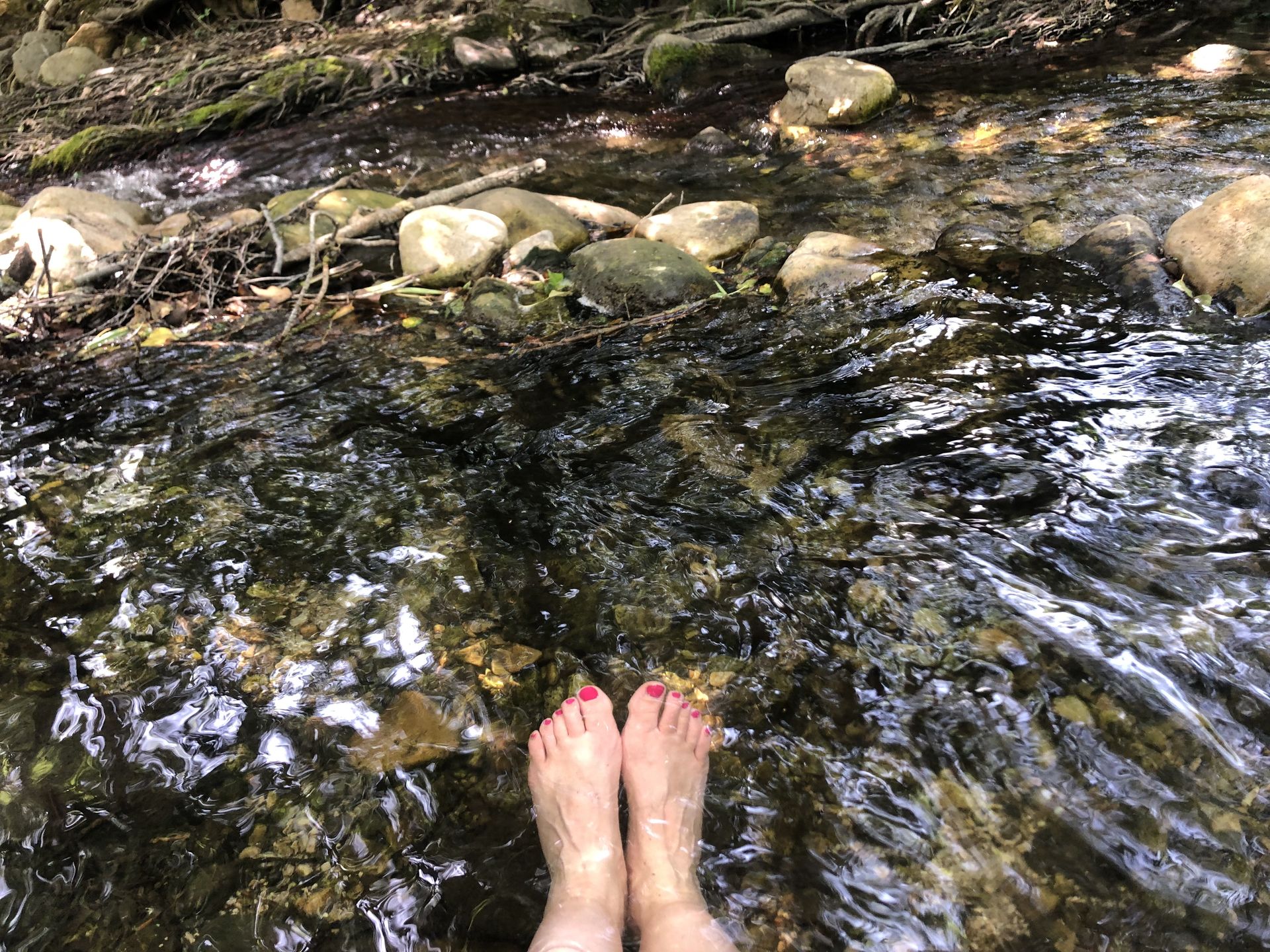 Une femme se rafraîchit les pieds dans l'eau de la rivière