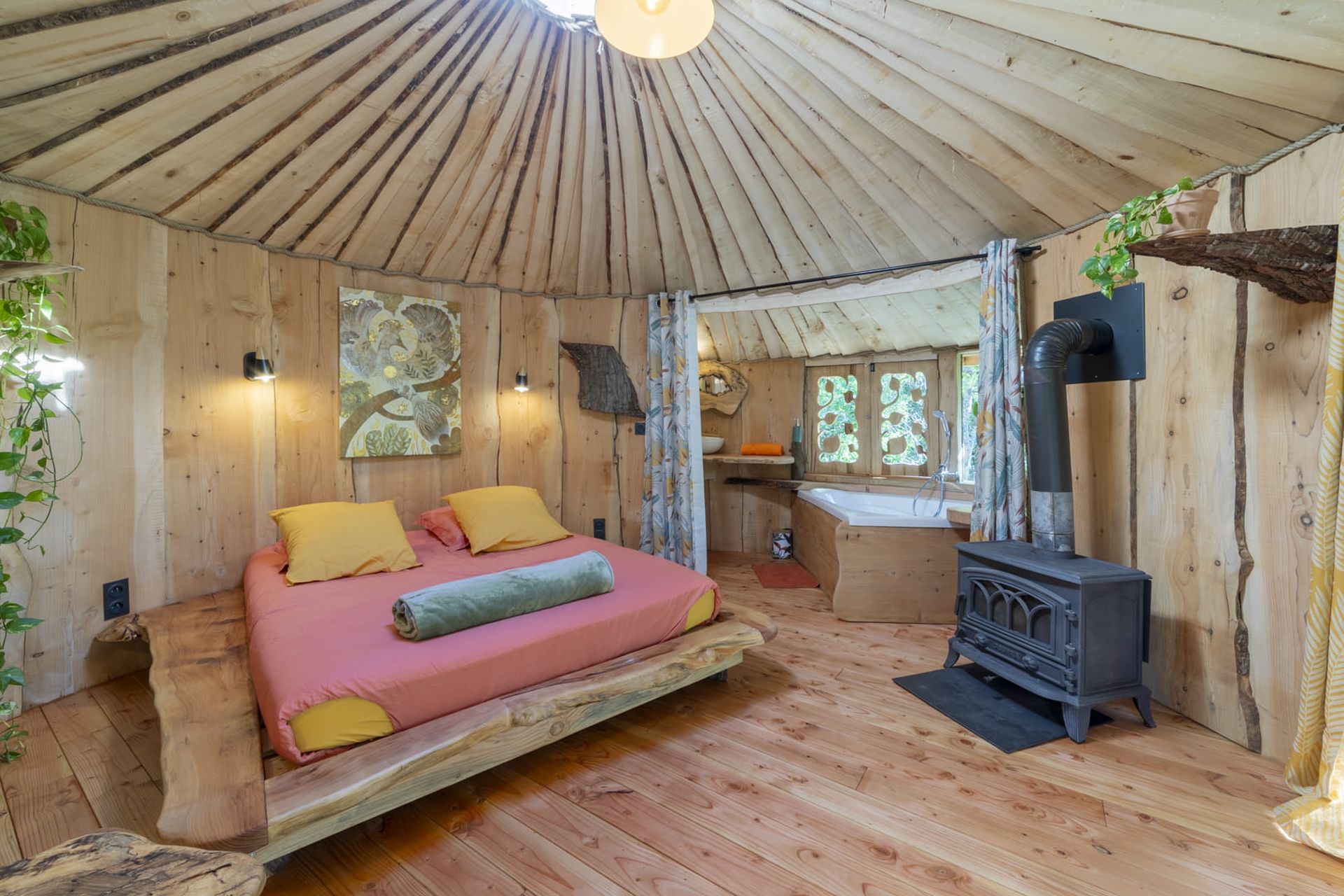 Vue sur la chambre, la baignoire-balnéo et le poêle à bois de L'Envol du Phénix, une cabane perchée à Cazilhac