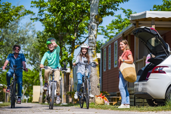 Famille à vélo dans les allées ombragées d'un camping