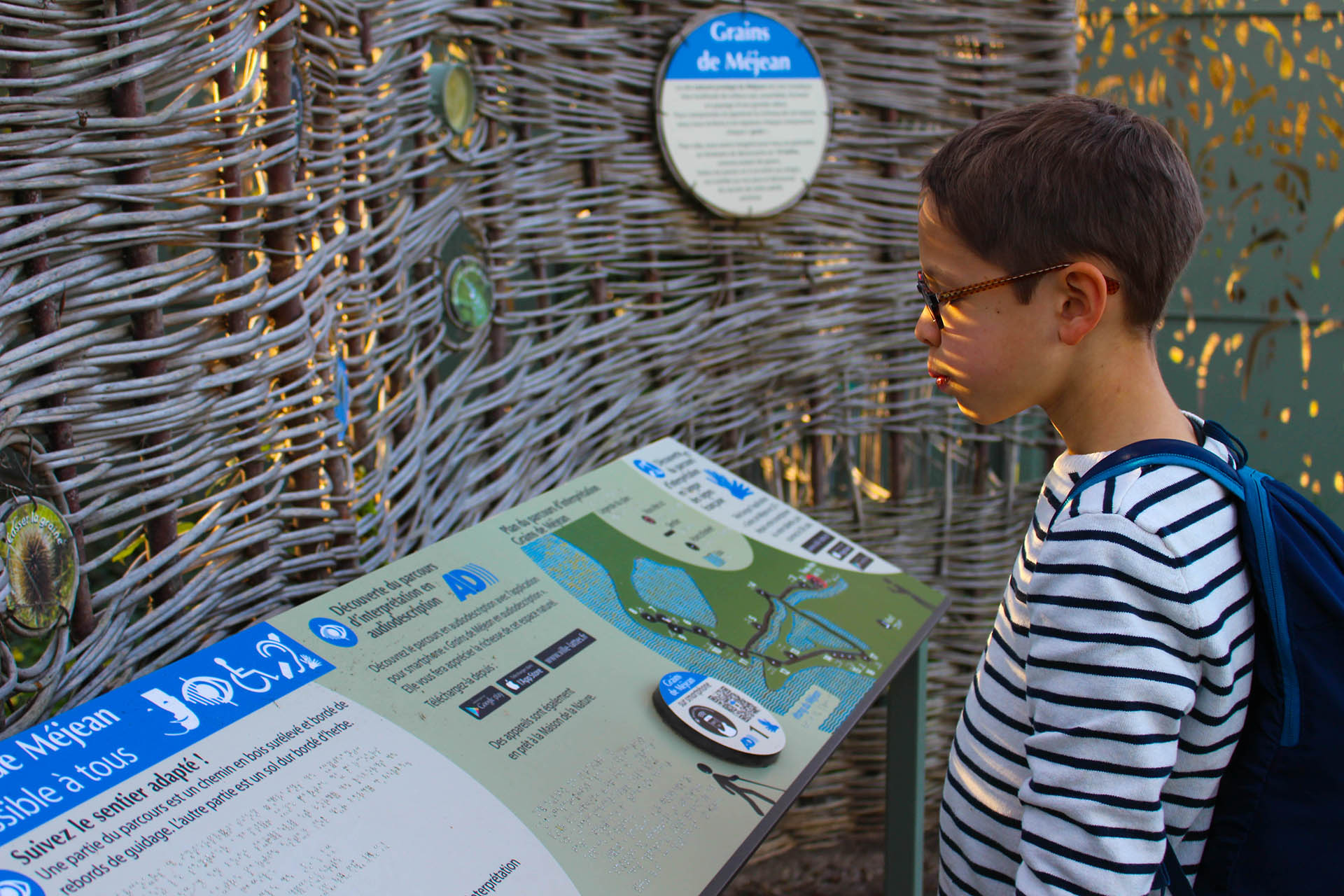 Jeune enfant qui lit un panneau explicatif à la maison de la nature à la Réserve naturelle du Méjean