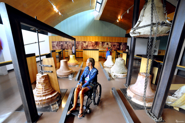 Une femme en situation de handicap moteur visite le Musée de la Cloche et de la Sonaille à Hérépian dans le Haut-Languedoc
