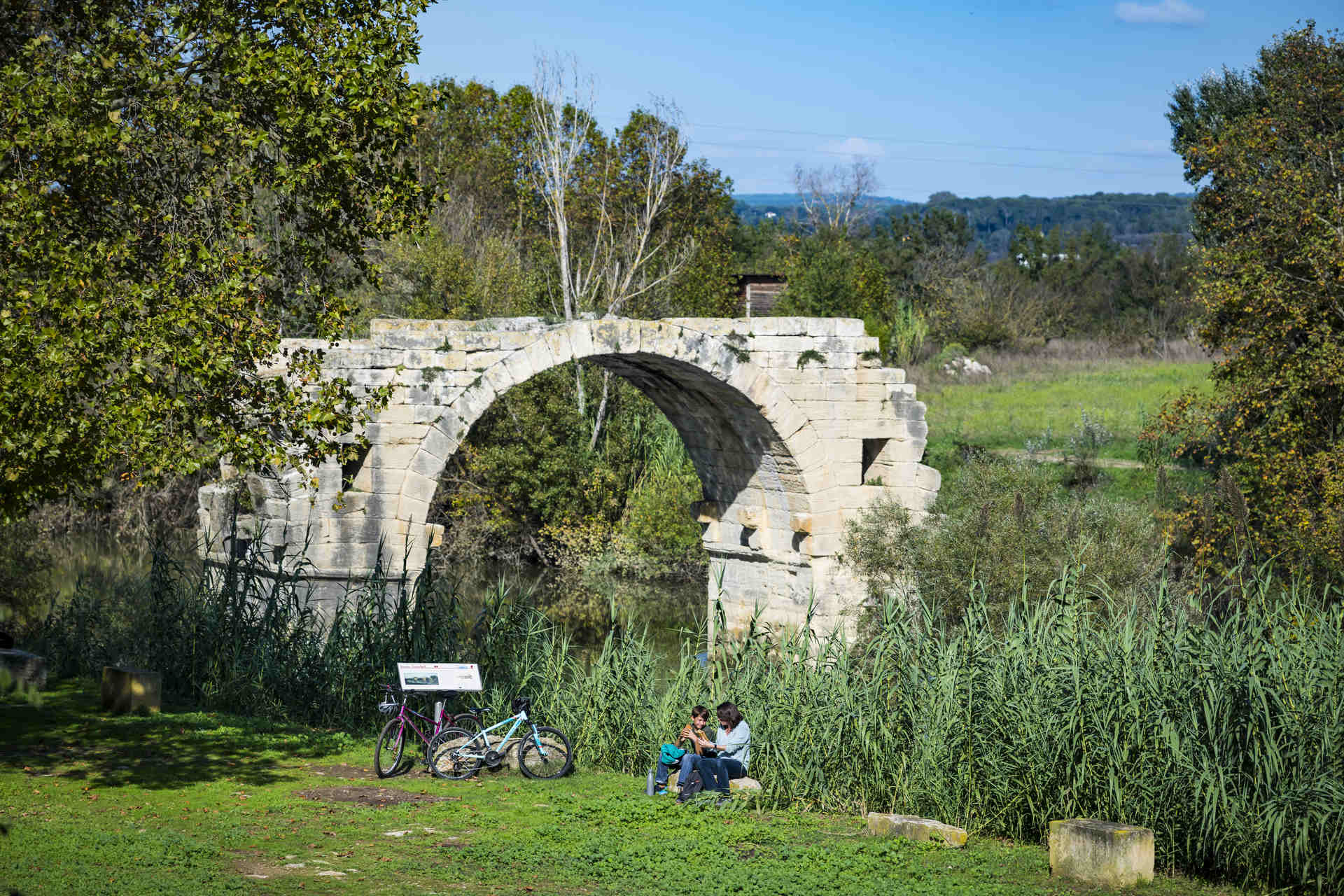 Ambrussum © Sam BIE Une maman et son fils devant le Pont Ambrois en vélo à Ambrussum