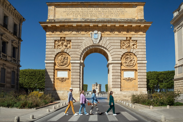 Groupe de jeunes traversant devant l'Arc de Triomphe de Montpellier