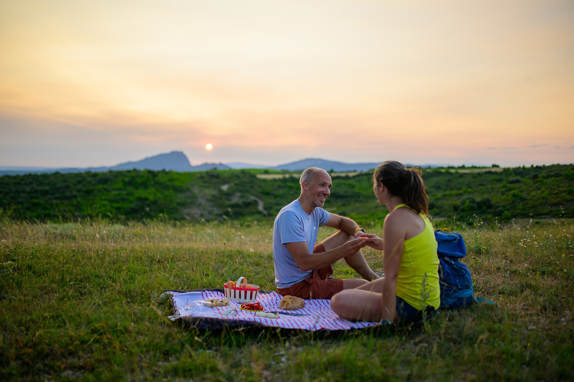 Couple qui pique-nique au coucher du soleil avec vue sur le Pic Saint-Loup à Guzargues