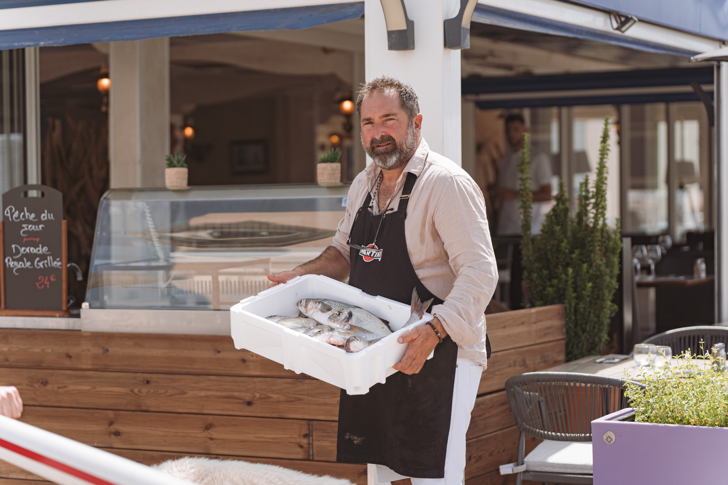 Photo du propriétaire de la Marine du pêcheur à Palavas-les-Flots sur la terrasse du restaurant avec la pêche du jour