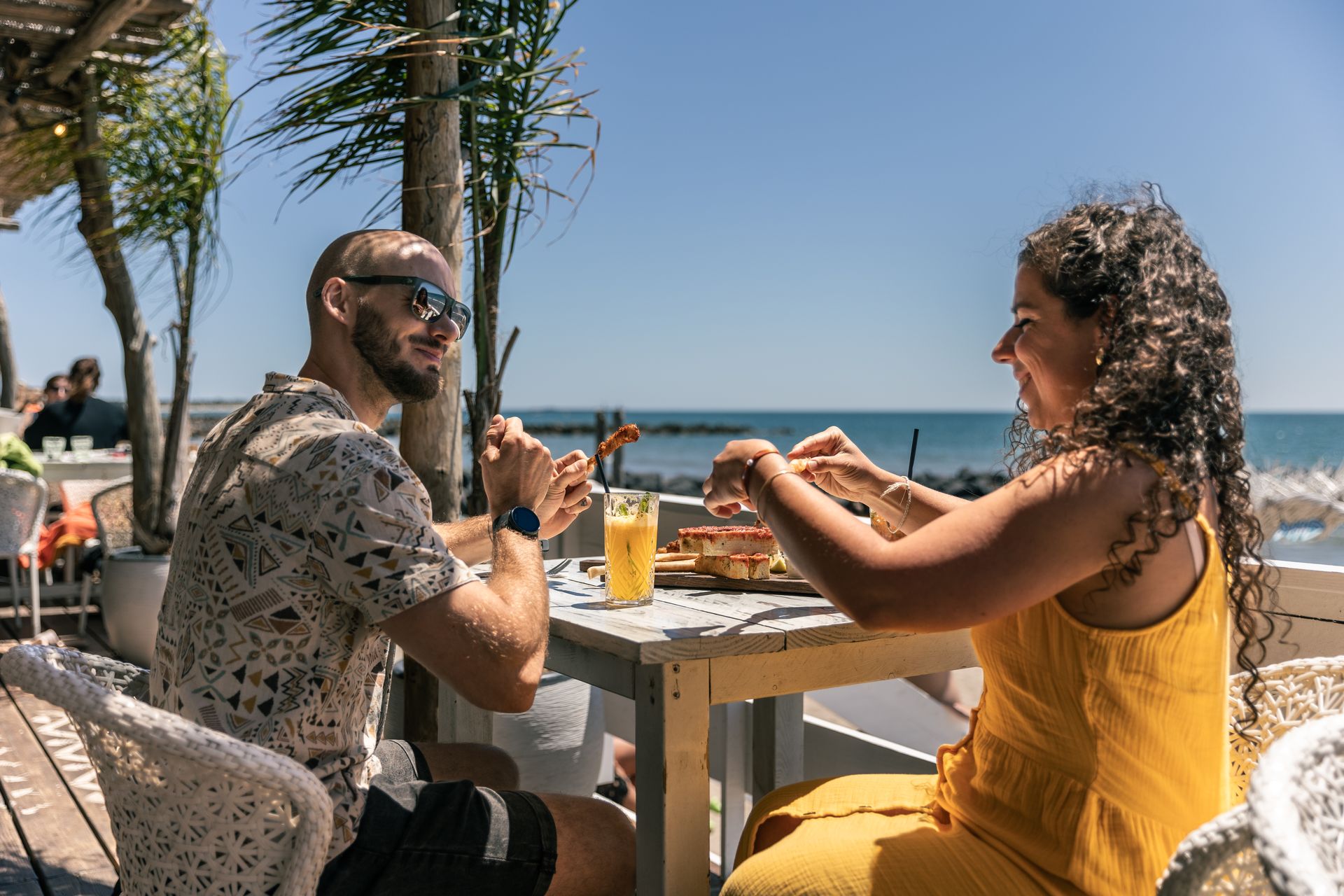 Un couple déjeune au soleil au bord de la mer à la Paillotte Chiringuito à Vias