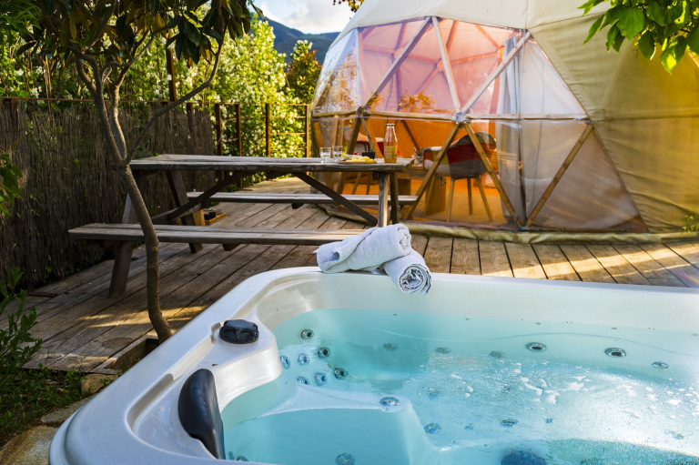 Vue sur un dôme, sa terrasse et son bain bouillonnant au camping du Caroux dans le Haut-Languedoc