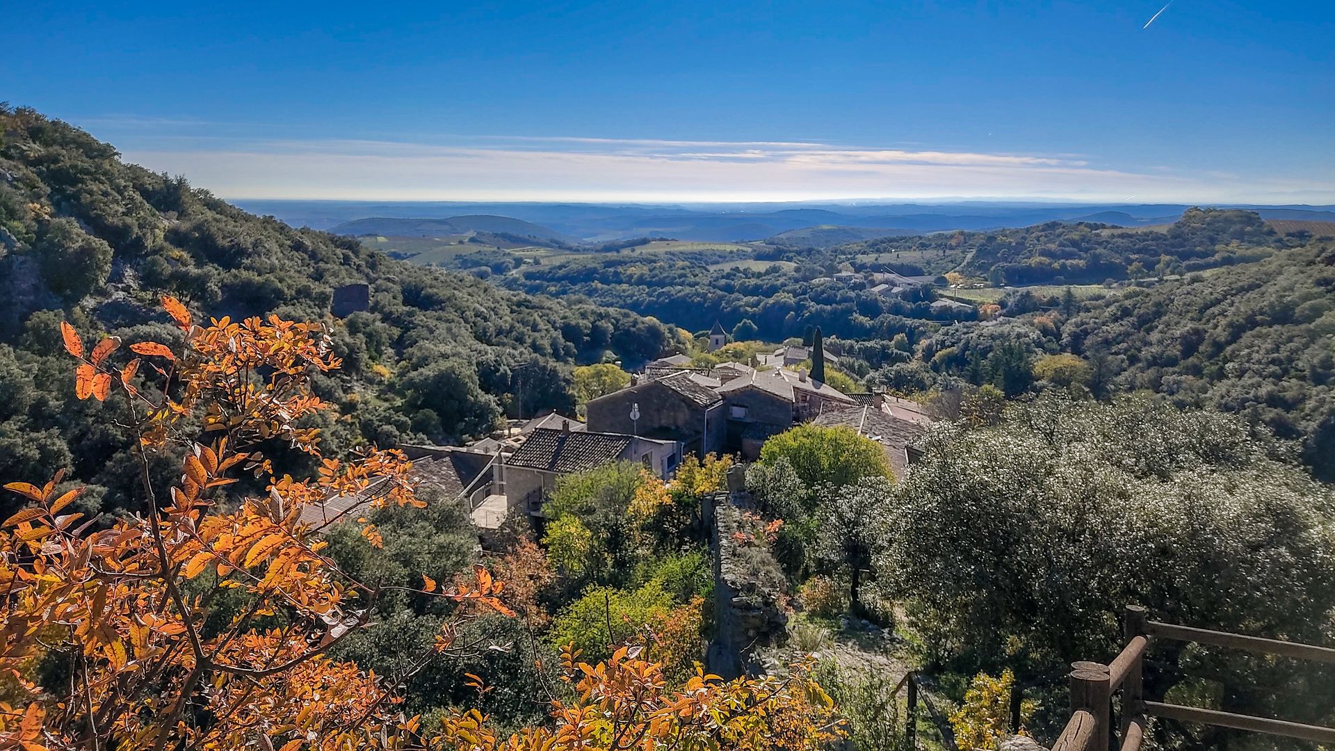 Vue sur le village médiéval de Cabrerolles, la plaine viticole et l'horizon méditerranéen depuis le castrum du village