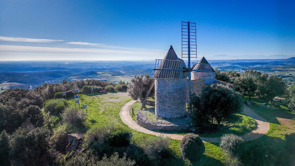 Vue sur les moulins de Faugères dans les avant-monts et son panorama sur la plaine viticole